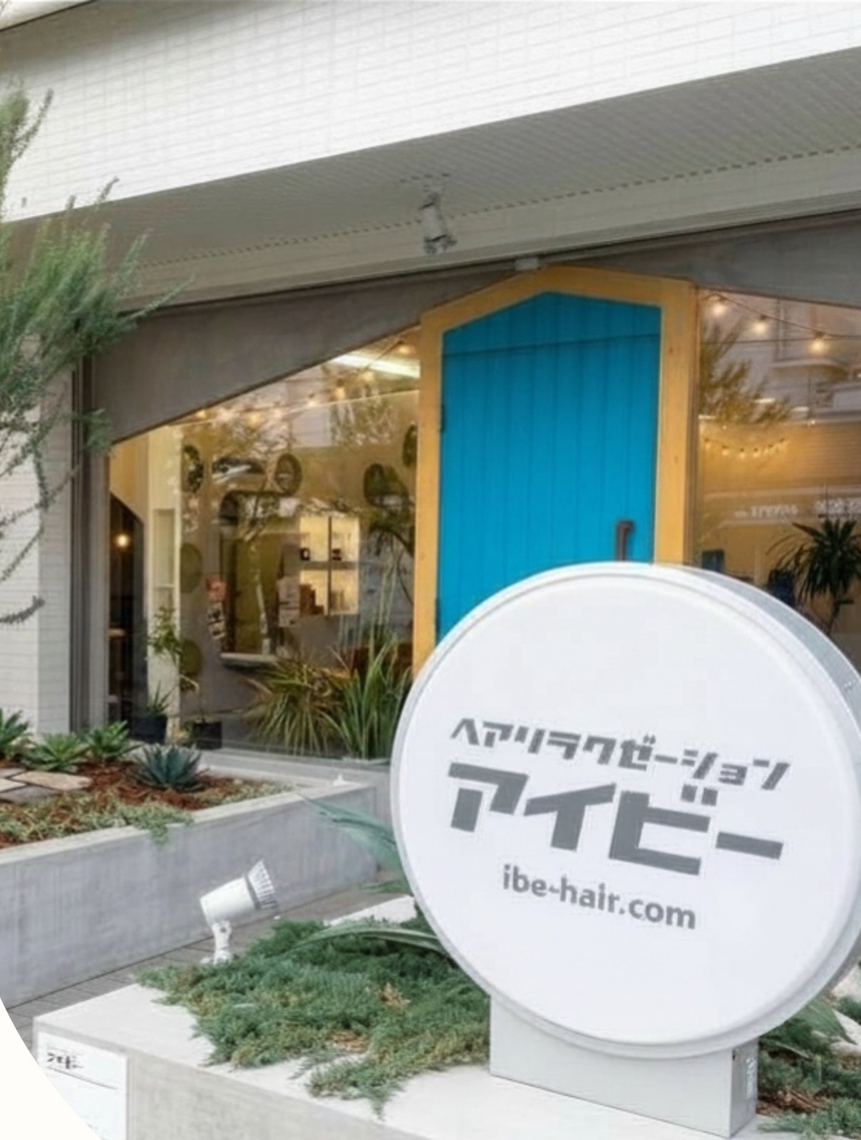 ヘアーリラクゼーション アイビーの店舗外観。青い扉と白い丸看板